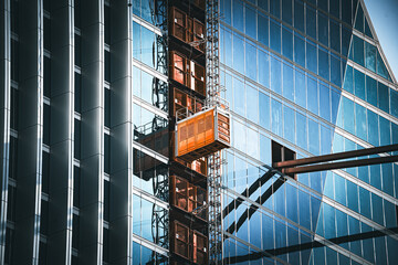 Modern skyscraper construction with external elevator and reflective glass facade © Tom Harwood