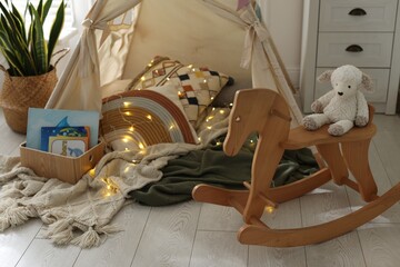 Cute wigwam with fairy lights and toys in stylish child's room © New Africa