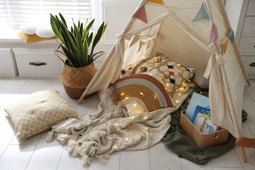 Cute wigwam with fairy lights and toys in stylish child's room © New Africa