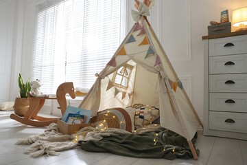 Cute wigwam with fairy lights and toys in stylish child's room © New Africa