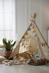 Cute wigwam with fairy lights and toys in stylish child's room © New Africa