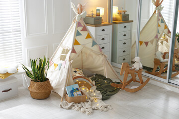 Cute wigwam with fairy lights and toys in stylish child's room © New Africa
