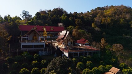 Obraz premium Wat pong yaeng nok temple complex featuring a golden buddha on a forest hillside