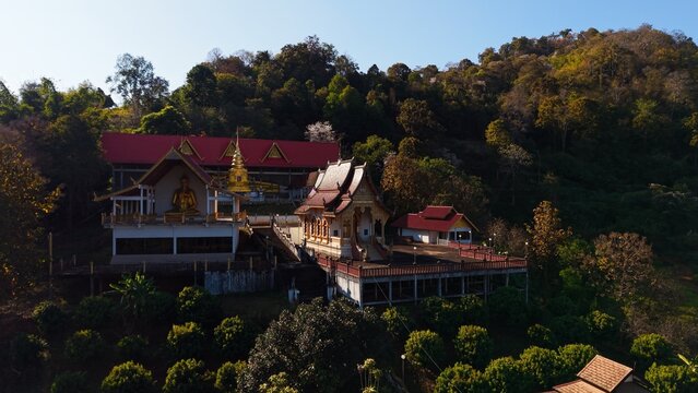 Wat pong yaeng nok temple complex featuring a golden buddha on a forest hillside