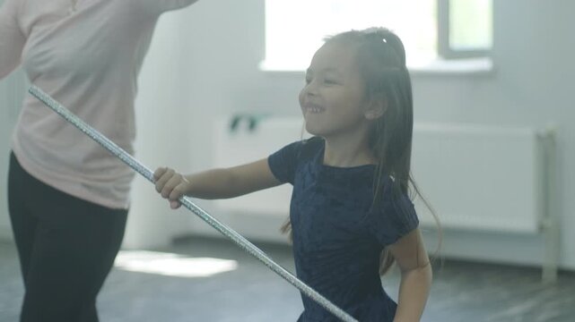 Child dancer's feet in golden high heel shoes training on a parquet floor during choreography lesson.