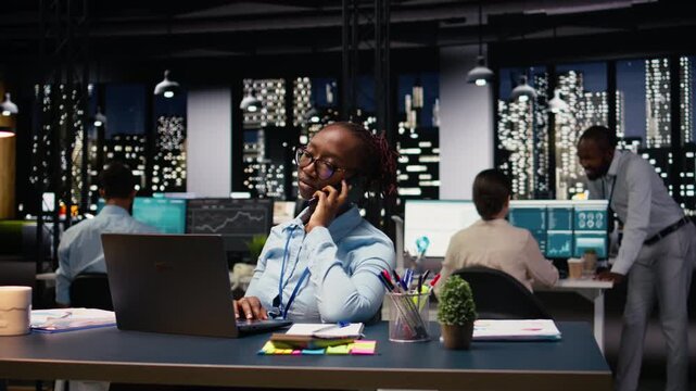 Businesswoman in office receiving call from client requesting assistance, using laptop. Entrepreneur talking over the phone with customer inquiring about commissioned project progress.