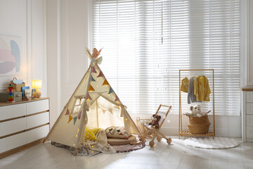 Cute wigwam with fairy lights and toys in stylish child's room © New Africa