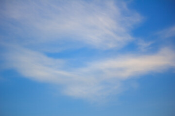 Naklejka premium Wide shot of a clear blue sky filled with wispy, soft white clouds drifting across the daytime horizon