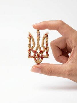 Hand Holding Ukrainian Tryzub Made of Wheat and Beads
