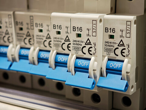 Close-up row of blue B16 miniature circuit breakers in an electrical distribution panel, off position switches for home wiring protection, safety equipment installation detail, no people