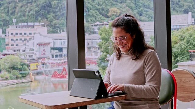 Smiling digital nomad woman working remotely in a cafe