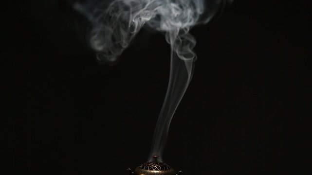Blue texture aroma smoke from incense stick in vintage old design metal box motion rising above on copy space dark background. Meditation, yoga, wellness, aroma calm relaxation concept