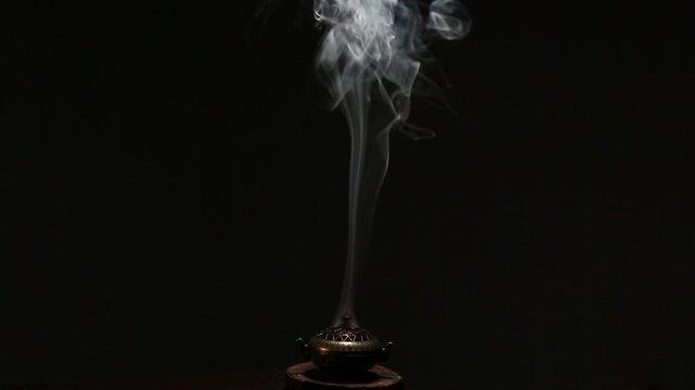 Blue texture smoke from incense aroma stick in vintage old design metal box motion rising above on copy space dark background. Meditation, yoga, wellness, aroma calm relaxation concept