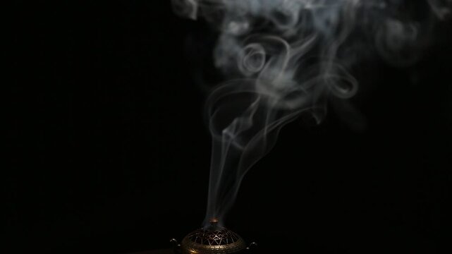Blue texture smoke from incense aroma stick in vintage old design metal box motion rising above on copy space dark background. Meditation, yoga, wellness, aroma calm relaxation concept