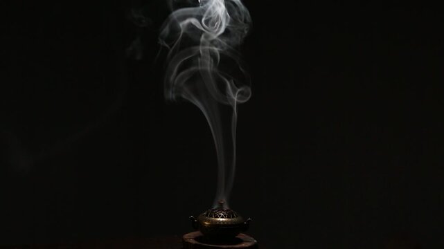 Blue texture smoke from incense aroma stick in vintage old design metal box motion rising above on copy space dark background. Meditation, yoga, wellness, aroma calm relaxation concept