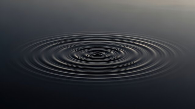 Concentric ripples spreading on the surface of dark, calm water.