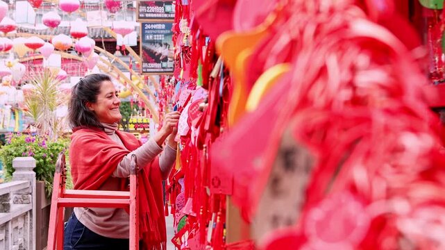 Woman smiling while hanging a wishing plaque in China