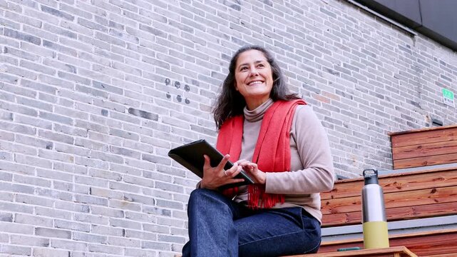 Mature digital nomad woman working on a tablet outdoors