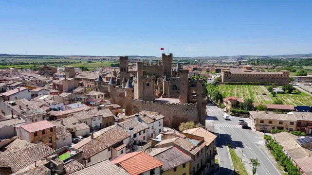 Aerial drone zoom out from Olite Castle in Navarre Spain. Smooth pull back from medium shot of medieval stone towers to extreme wide view of the historic Royal Palace and surrounding town.
