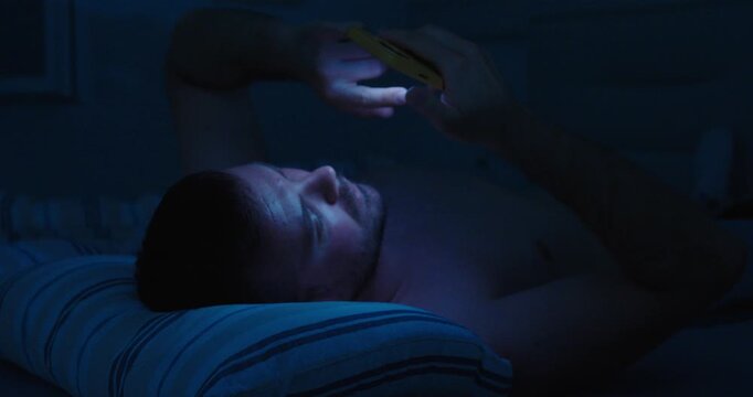 Insomniac Man Using Smartphone in Bed Late at Night
