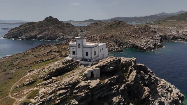 4K drone tracking right then flying over Korakas Lighthouse to reveal rugged rocky terrain, Paros, Greece