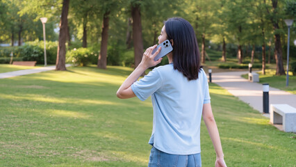 Fototapeta premium Woman talking on smartphone in apartment, ​Female holding phone call outdoors, ​Back view of woman calling indoors, ​Young woman with phone in living room, ​Casual lifestyle phone conversation,