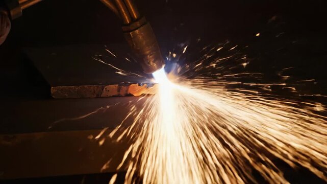 Close-up of a bright acetylene torch intensely cutting through thick steel, creating a brilliant shower of fiery sparks in an industrial setting.