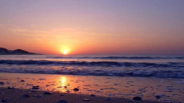 Peaceful coastal footage with small breakers washing onto shoreline at sundown, golden reflection and pastel evening sky for travel use