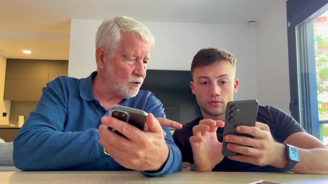 A young man teaches an older man how to use his smartphone, demonstrating modern technology and intergenerational learning at home.