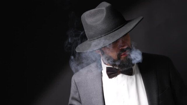 Mafia. Man in hat smoking cigar on dark background