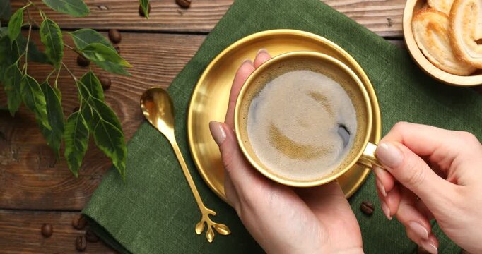 Woman taking cup with aromatic coffee at wooden table, top view