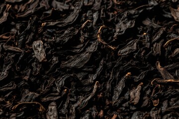 Fototapeta premium Heap of dry black tea leaves. Closeup macro texture of withered plant material for hot beverage. Natural organic ingredient for herbal infusion.