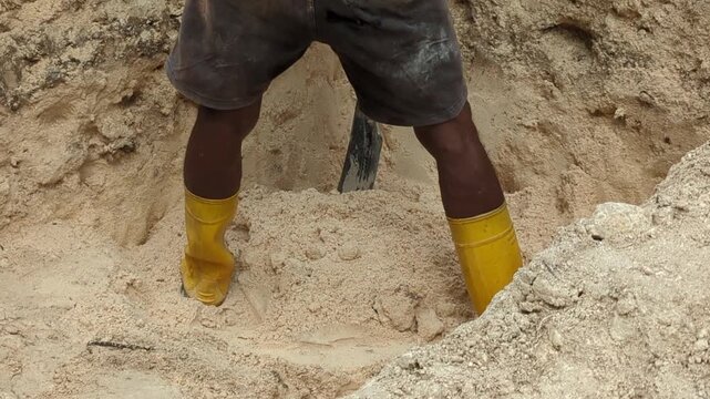 Close-up footage of a construction worker digging a septic tank pit at a building site. Ideal for sanitation infrastructure, excavation, wastewater management, and construction industry concepts.