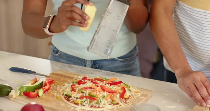 African American team starting pizza on kitchen counter with grater slicing mushrooms for baking