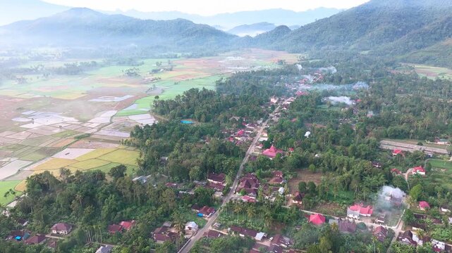 Claude merespons: Aerial view of a rural village with road, rice fields and mountains in the background surrounded by tropical forest in Payakumbuh, West Sumatra, IndonesiaAerial view of a rural v