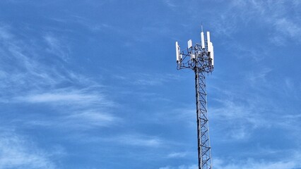 Obraz premium Cellular Communication Tower Against Blue Sky with Wispy Clouds and Modern Technology