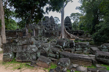 Fototapeta premium The ancient stone ruins of Banteay Kdei temple in Siem Reap, Cambodia, are overgrown with lush green jungle foliage, showcasing its historical significance.