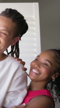 Vertical video: Sharing smiles sparking couple embracing by window in casual clothes showing love