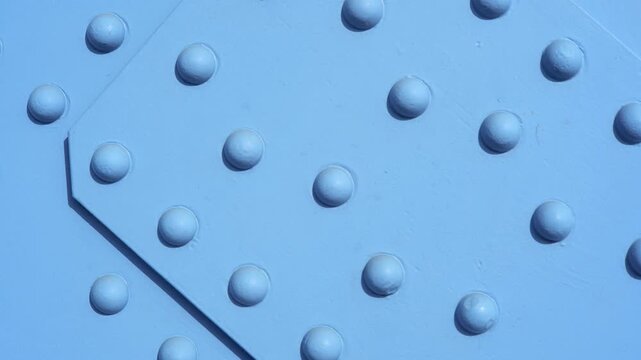 Close-up of light blue painted riveted steel beams with round bolt heads and diagonal joint, industrial metal structure texture for engineering, construction and bridge material background, no people