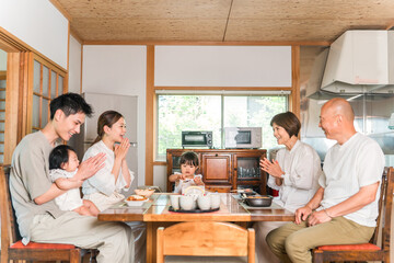 Fototapeta premium A three-generation family eating a meal at the dinner table (parents' home, visiting family, family gathering)
