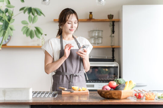 An Asian woman using a smartphone app in her kitchen/dining room at home.
