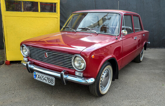 Pristine red VAZ-2101 Zhiguli sedan, classic Soviet car features iconic round headlights, chrome bumpers, and whitewall tires, showcasing well maintained vintage aesthetic