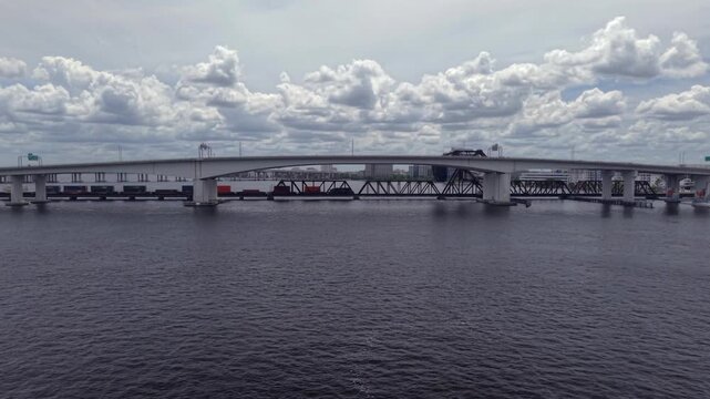 Aerial view of the Acosta Bridge and FEC Railway Bridge spanning the St. Johns River under a cloudy sky in Jacksonville, Florida, United States.