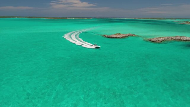 Speedboat carving a sharp turn around rocky cays, aerial tracking