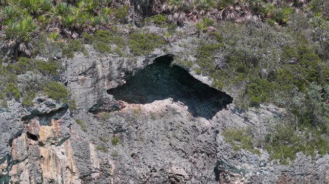 Aerial pull back shot of limestone island cliff and sea cave