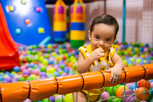 Happy one year old latina toddler girl playing in an indoor playground, representing healthy lifestyle, wellness and early childhood development.