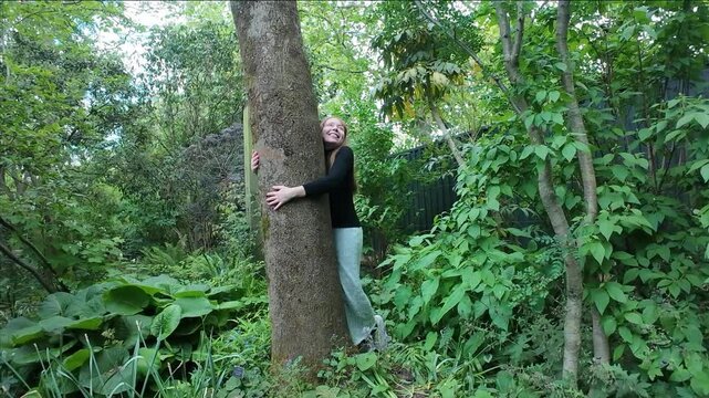 Woman happily hugs tree trunk in a park