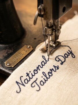  Extreme Macro Close-Up of Antique Sewing Machine Needle Stitching "National Tailors Day" on Cream Fabric with Engraved June 3 Plate
