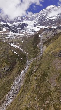 Aerial view of the rugged Monte Rosa massif with its glacier and rocky slopes under a cloudy sky in Alagna Valsesia, Piedmont, Italy.