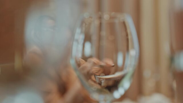 Woman at table overwhelmed with paper, crumpled receipts and bills on tabletop, head in hand, blurred wineglass in foreground, dim cafe ambience, glasses askew, deadline tension and visible fatigue